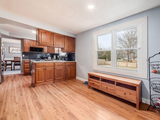 kitchen featuring tasteful backsplash, stainless steel refrigerator, a textured ceiling, and light hardwood / wood-style floors