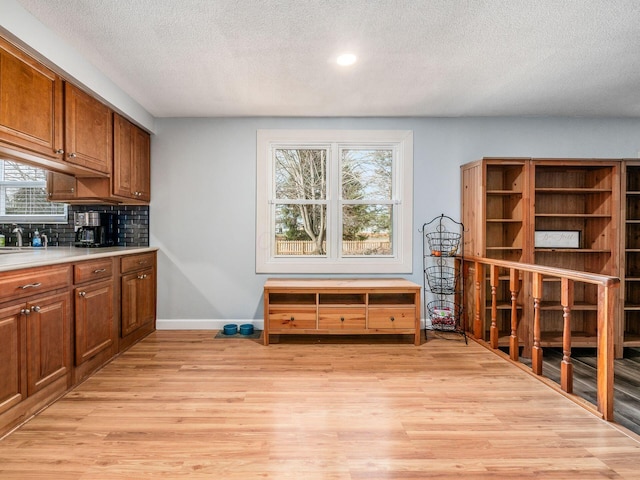 interior space featuring decorative backsplash, light hardwood / wood-style flooring, and a textured ceiling