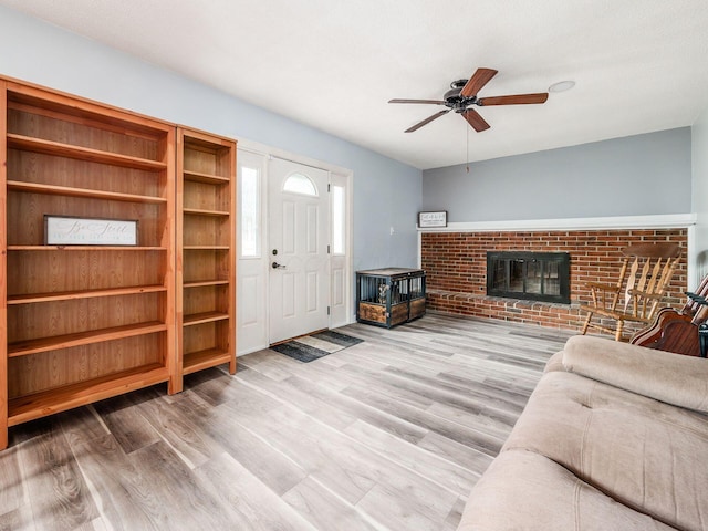 living room with ceiling fan, hardwood / wood-style floors, and a brick fireplace