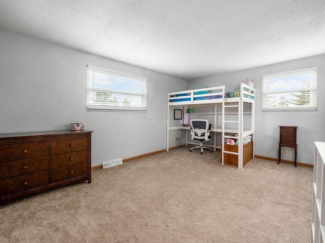 bedroom with light colored carpet and a textured ceiling