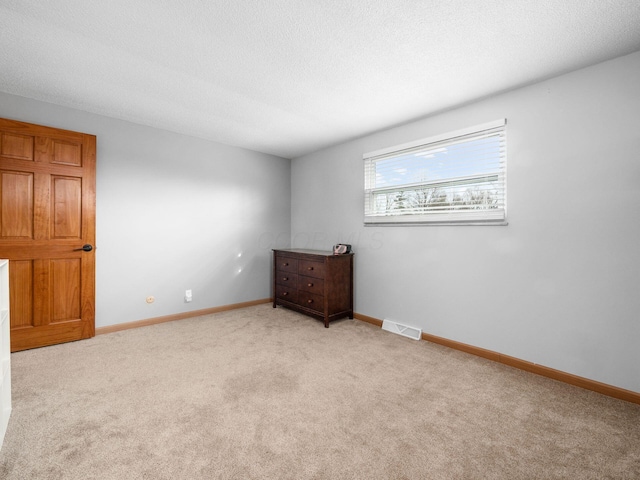 carpeted empty room with a textured ceiling