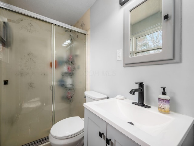 bathroom featuring vanity, a textured ceiling, a shower with door, and toilet