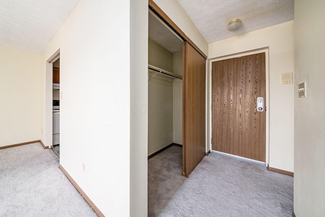 hallway featuring a textured ceiling and light colored carpet