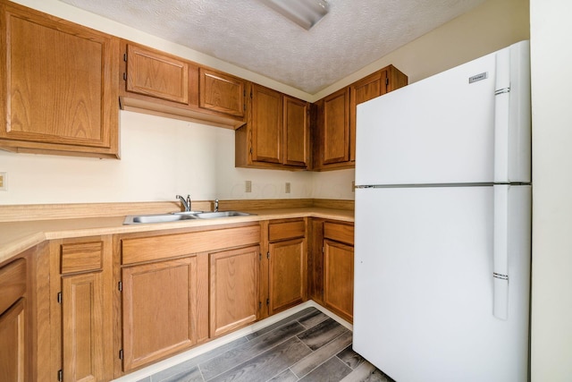 kitchen featuring sink, white refrigerator, and a textured ceiling