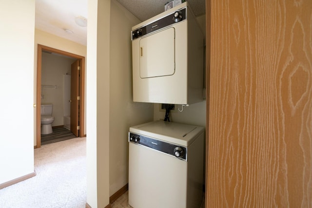 clothes washing area with light carpet and stacked washer and dryer