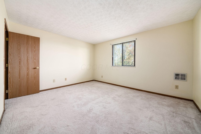 spare room with a textured ceiling and light carpet