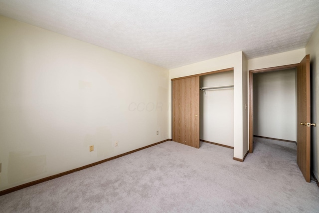 unfurnished bedroom featuring light colored carpet, a textured ceiling, and a closet