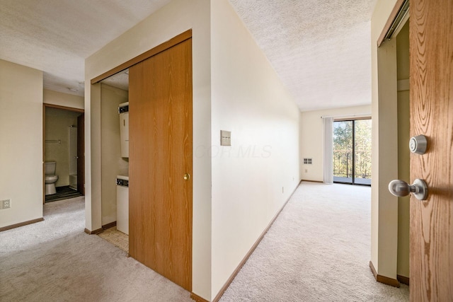 corridor featuring light carpet and a textured ceiling