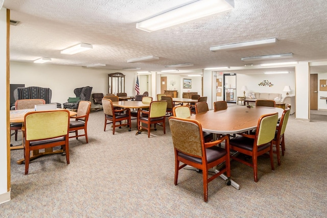 dining space with light colored carpet and a textured ceiling