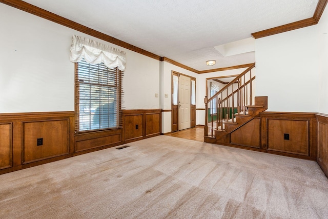 carpeted foyer entrance featuring ornamental molding and a textured ceiling