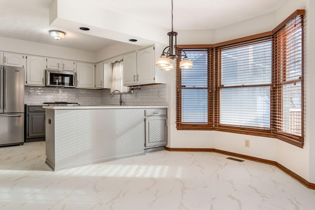 kitchen featuring hanging light fixtures, appliances with stainless steel finishes, backsplash, and a chandelier