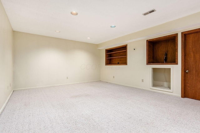 unfurnished room with light carpet and built in shelves