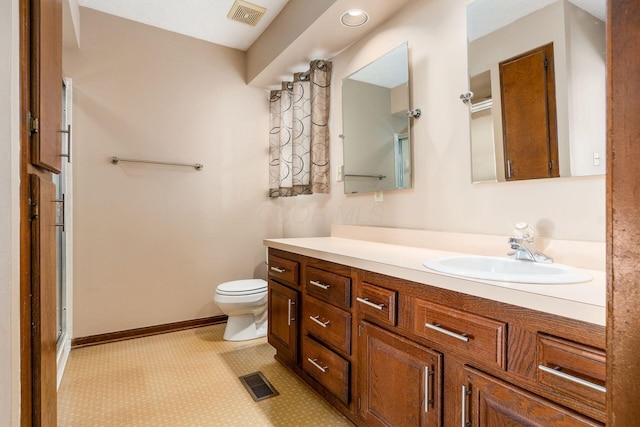 bathroom with tile patterned floors, vanity, toilet, and a shower with door