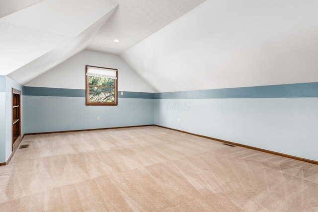 bonus room featuring lofted ceiling, light carpet, and a textured ceiling