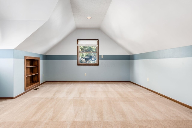 bonus room featuring light carpet, lofted ceiling, and a textured ceiling