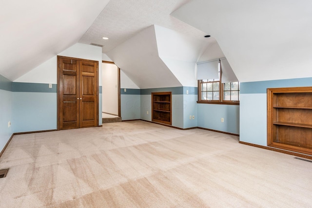 additional living space with light carpet, built in features, lofted ceiling, and a textured ceiling