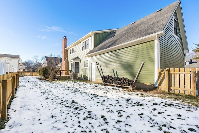 snow covered back of property featuring central air condition unit