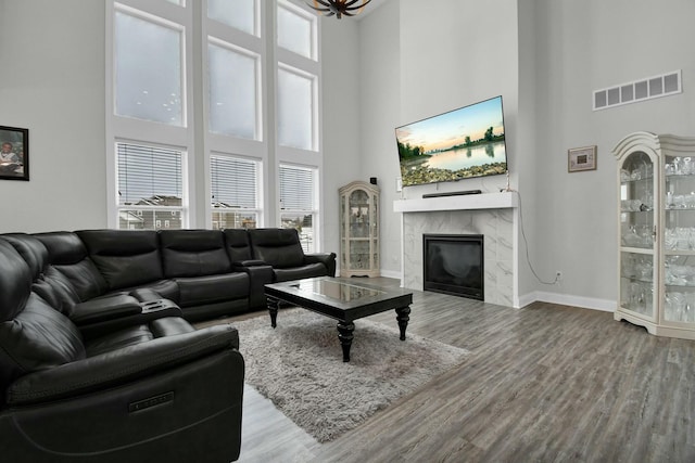 living room featuring hardwood / wood-style flooring, a premium fireplace, and a high ceiling