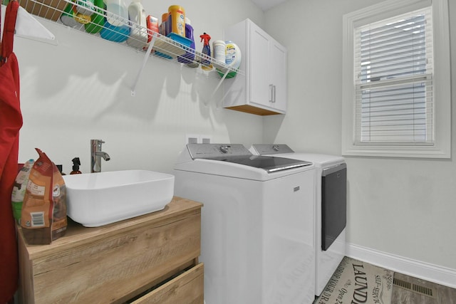 laundry area with cabinets, wood-type flooring, separate washer and dryer, and sink