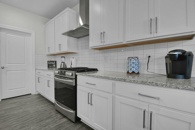 kitchen with white cabinets, backsplash, hardwood / wood-style flooring, stainless steel gas range oven, and wall chimney exhaust hood