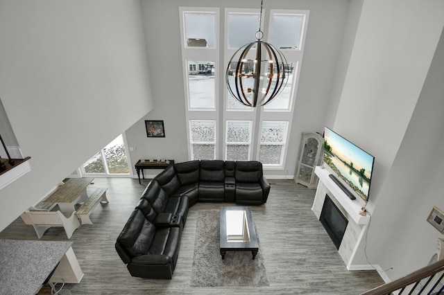 living room with wood-type flooring, a towering ceiling, plenty of natural light, and a chandelier