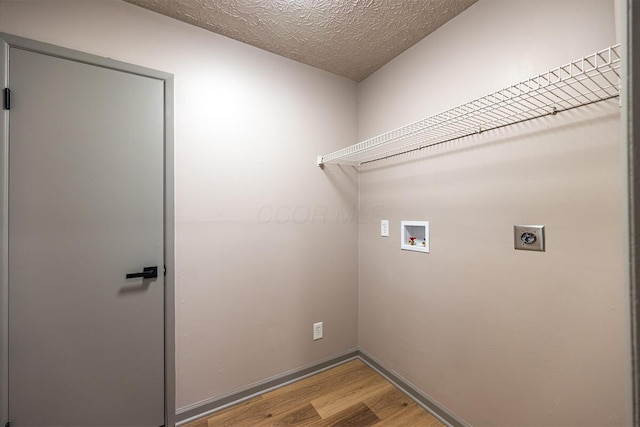 laundry area featuring light hardwood / wood-style floors, washer hookup, a textured ceiling, and electric dryer hookup