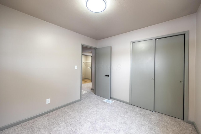 unfurnished bedroom with a closet and light carpet