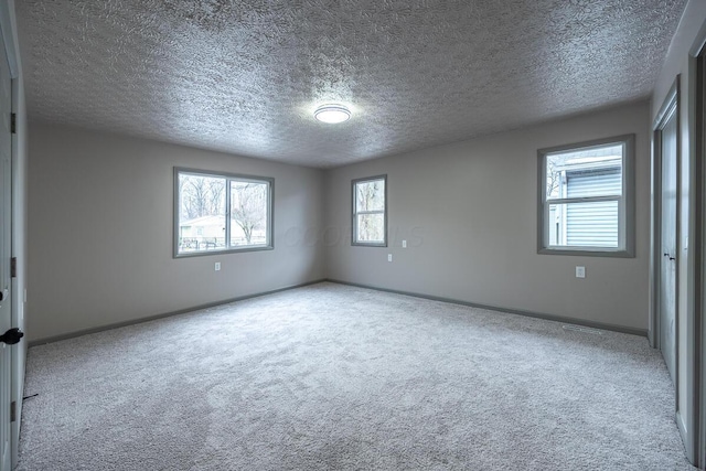 unfurnished room featuring a textured ceiling and light carpet