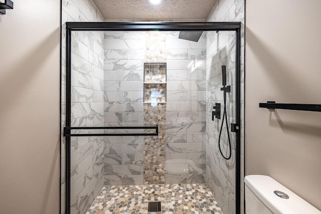 bathroom with a textured ceiling, an enclosed shower, and toilet