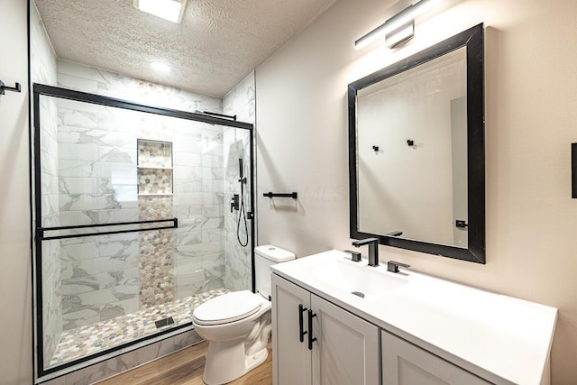 bathroom with toilet, hardwood / wood-style floors, a textured ceiling, an enclosed shower, and vanity