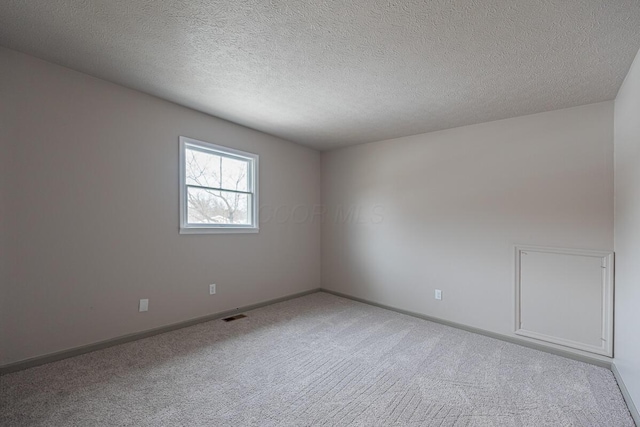 carpeted empty room with a textured ceiling