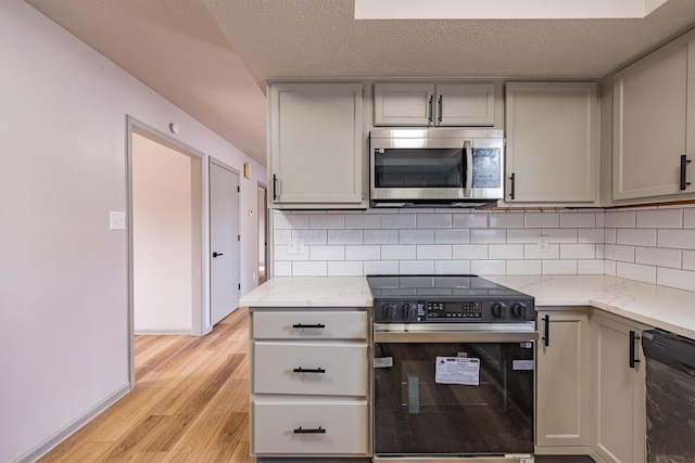 kitchen featuring backsplash, range with electric stovetop, light stone countertops, and dishwasher