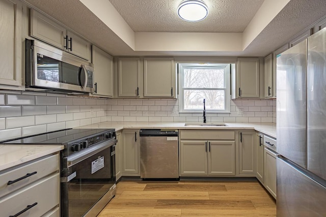 kitchen with sink, light hardwood / wood-style flooring, appliances with stainless steel finishes, tasteful backsplash, and a textured ceiling