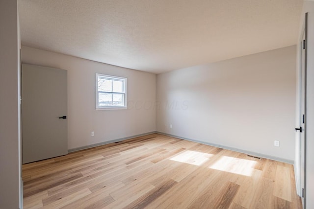 unfurnished room featuring a textured ceiling and light hardwood / wood-style floors