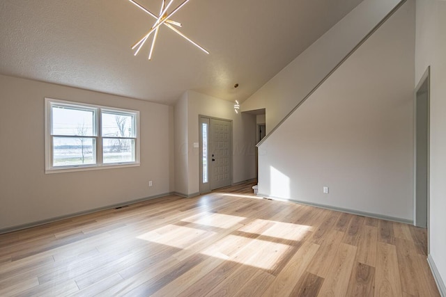 interior space with an inviting chandelier, lofted ceiling, and light wood-type flooring