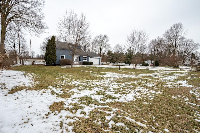 yard layered in snow featuring a garage