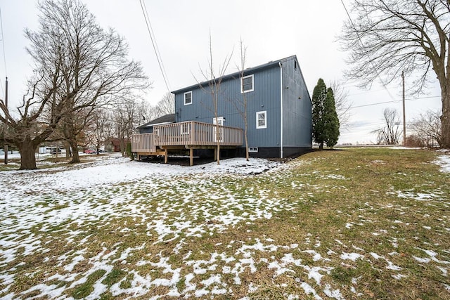 snow covered house with a deck and a lawn