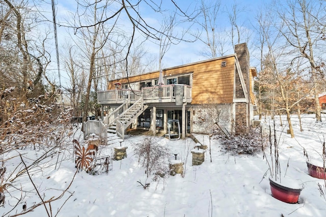 snow covered rear of property with a wooden deck