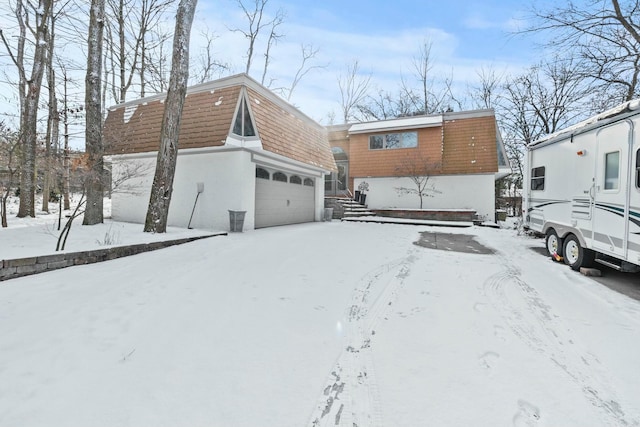 snow covered back of property with a garage