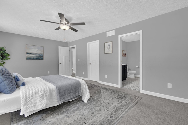 bedroom with ensuite bathroom, carpet, a textured ceiling, and ceiling fan