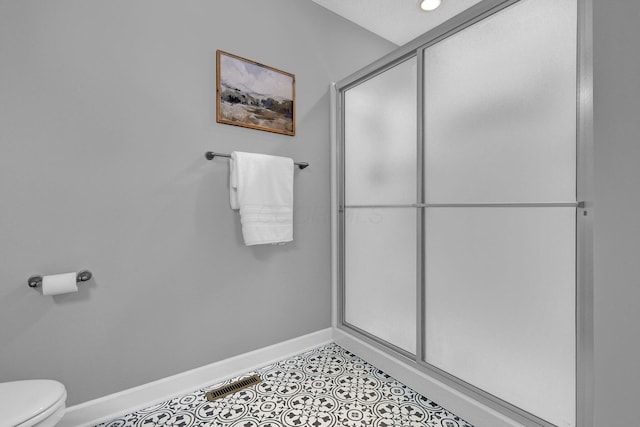 bathroom with a shower with shower door and toilet