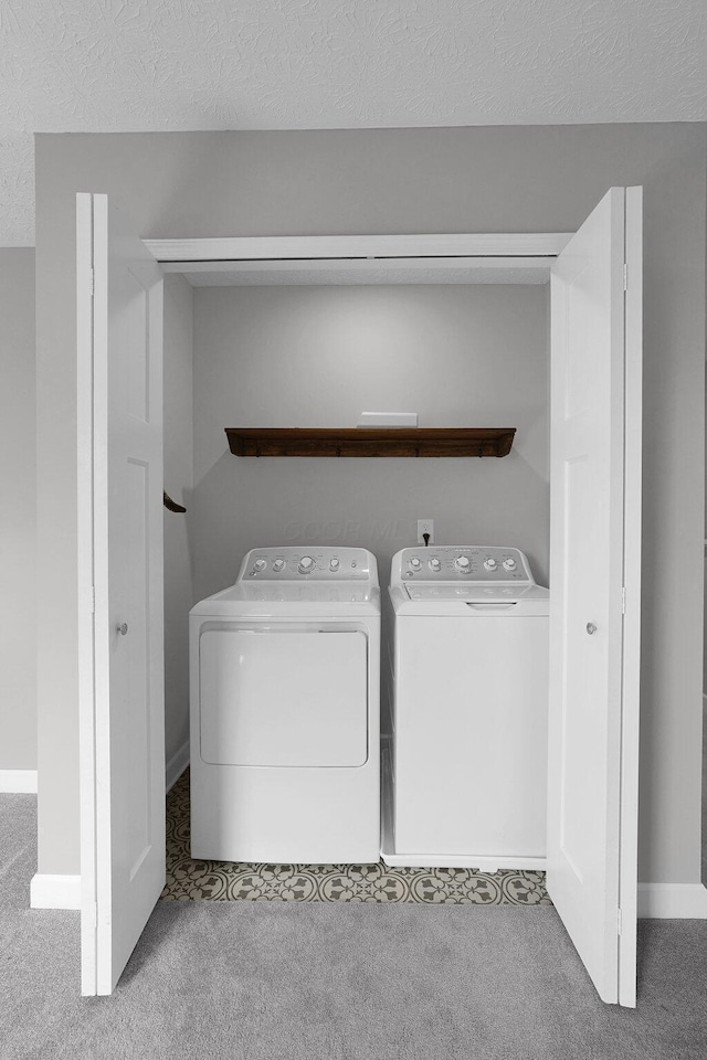 laundry room with light carpet, a textured ceiling, and washing machine and clothes dryer