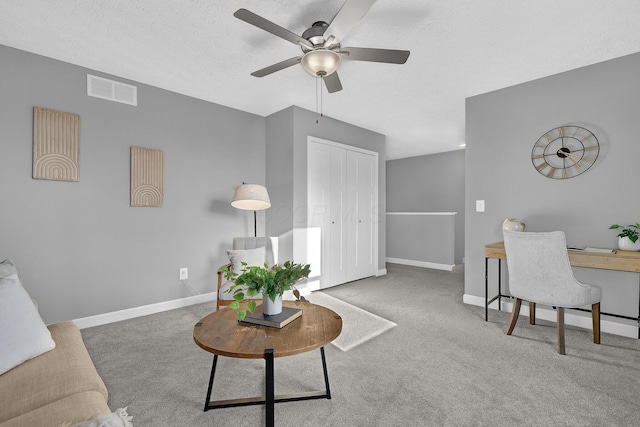 carpeted living room featuring ceiling fan and a textured ceiling