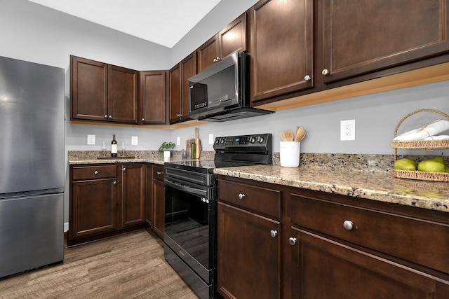 kitchen featuring stainless steel refrigerator, dark brown cabinetry, light stone counters, light hardwood / wood-style floors, and black range with electric cooktop