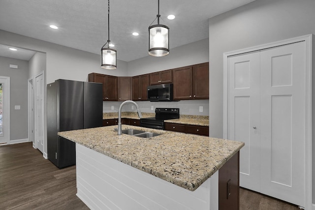 kitchen with sink, light stone counters, decorative light fixtures, an island with sink, and stainless steel appliances