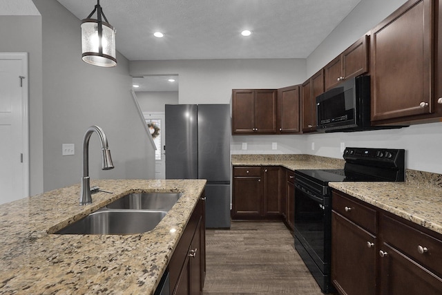 kitchen with sink, light stone counters, dark brown cabinets, hanging light fixtures, and black range with electric cooktop