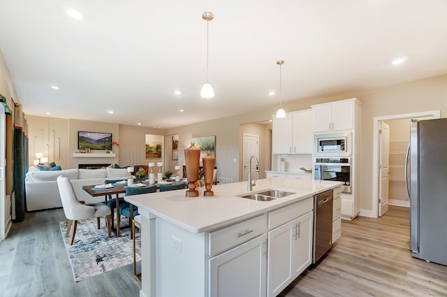 kitchen with sink, white cabinetry, decorative light fixtures, a center island with sink, and appliances with stainless steel finishes