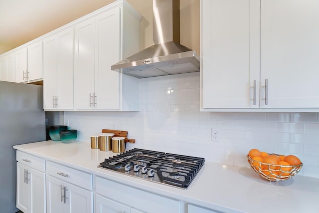 kitchen with tasteful backsplash, appliances with stainless steel finishes, wall chimney exhaust hood, and white cabinets