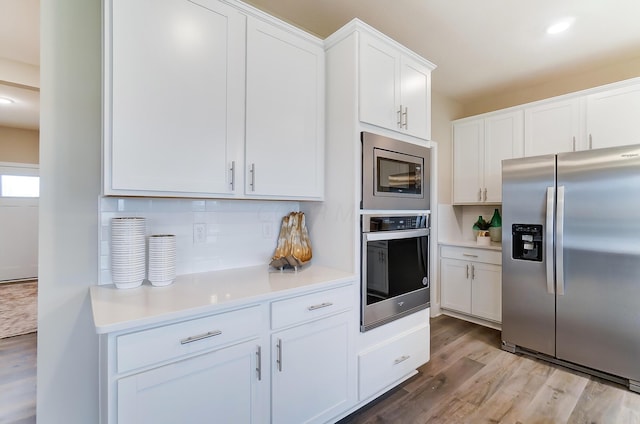 kitchen featuring white cabinetry, stainless steel appliances, tasteful backsplash, and light wood-type flooring