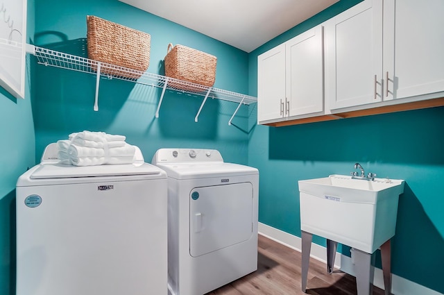 laundry room with cabinets, sink, light hardwood / wood-style floors, and washing machine and dryer